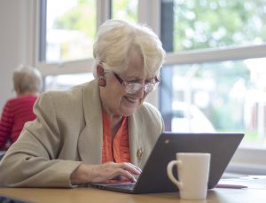 Older lady smiling as she looks at computer tablet