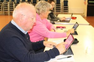Two older people looking at ipads in a community classroom