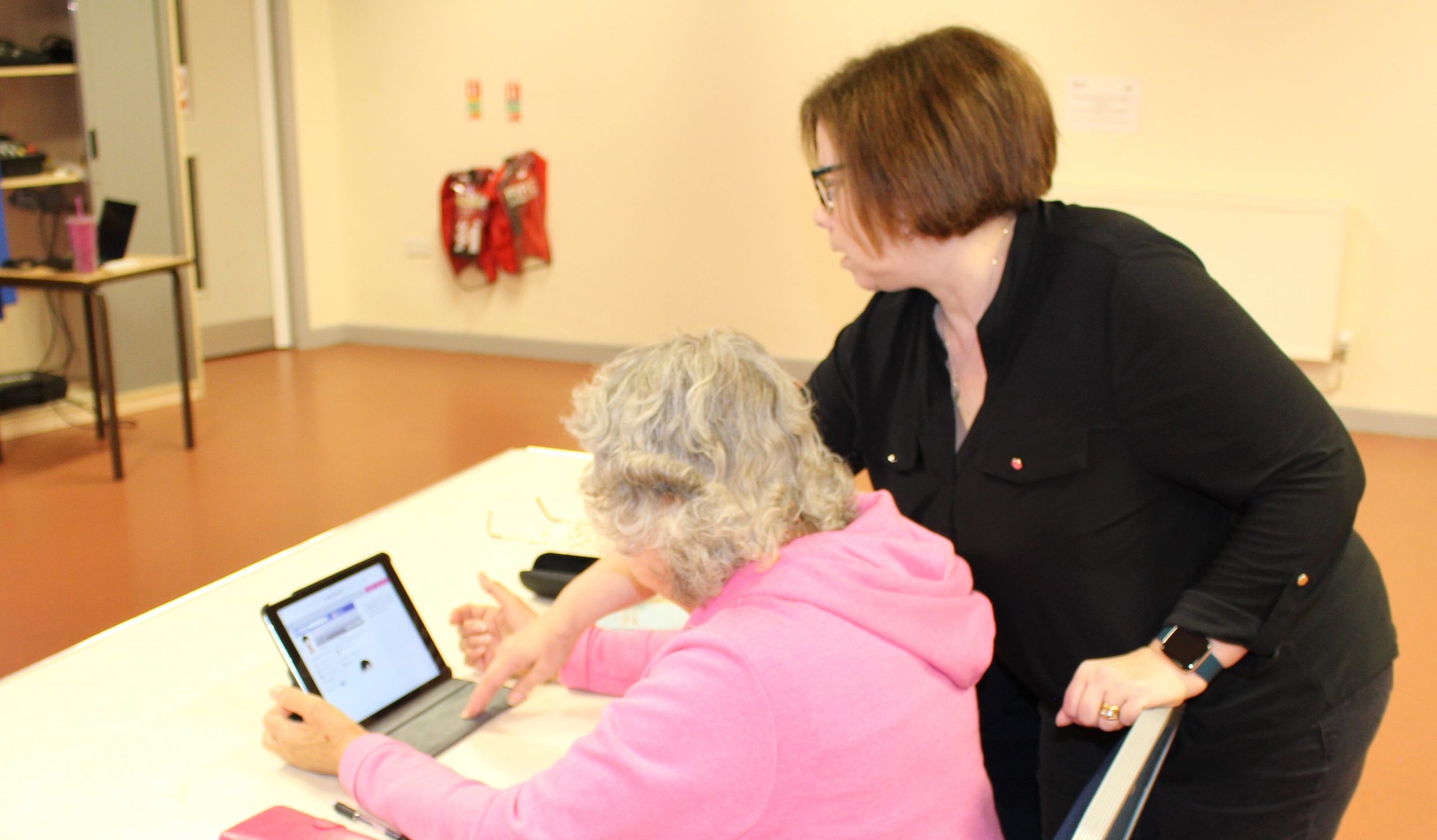 Younger woman helping older woman with ipad