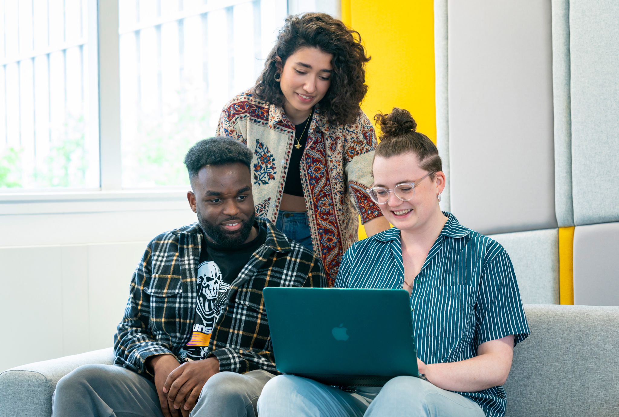 3 young people on sofa looking at laptop