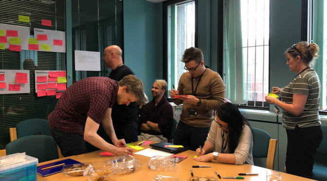 A group of people writing sticky notes and sticking them on a white board