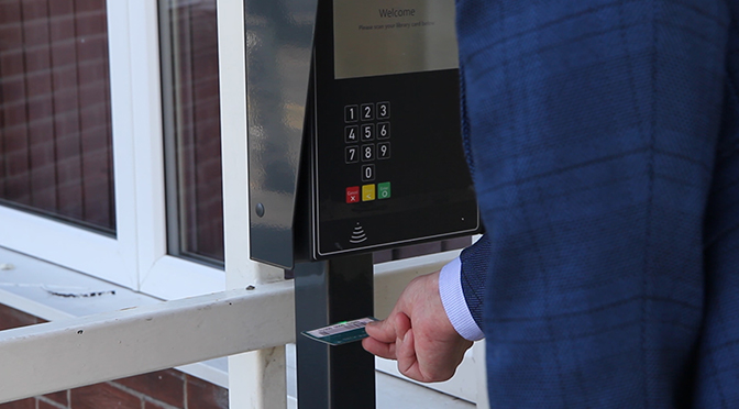 Person scanning library card in card reader machine