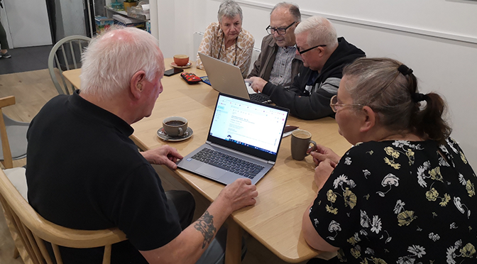 People chatting with computers open and hot drinks