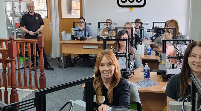 A group of people in a classroom with 3D printers