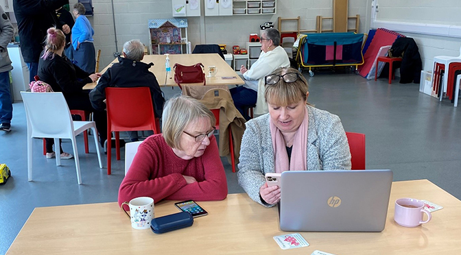 Two people in a community room looking at a computer