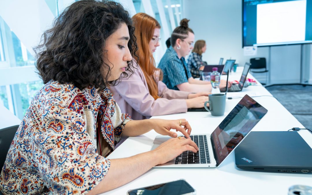 Young people on laptops in a classroom