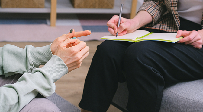 Two people's hands, one taking notes