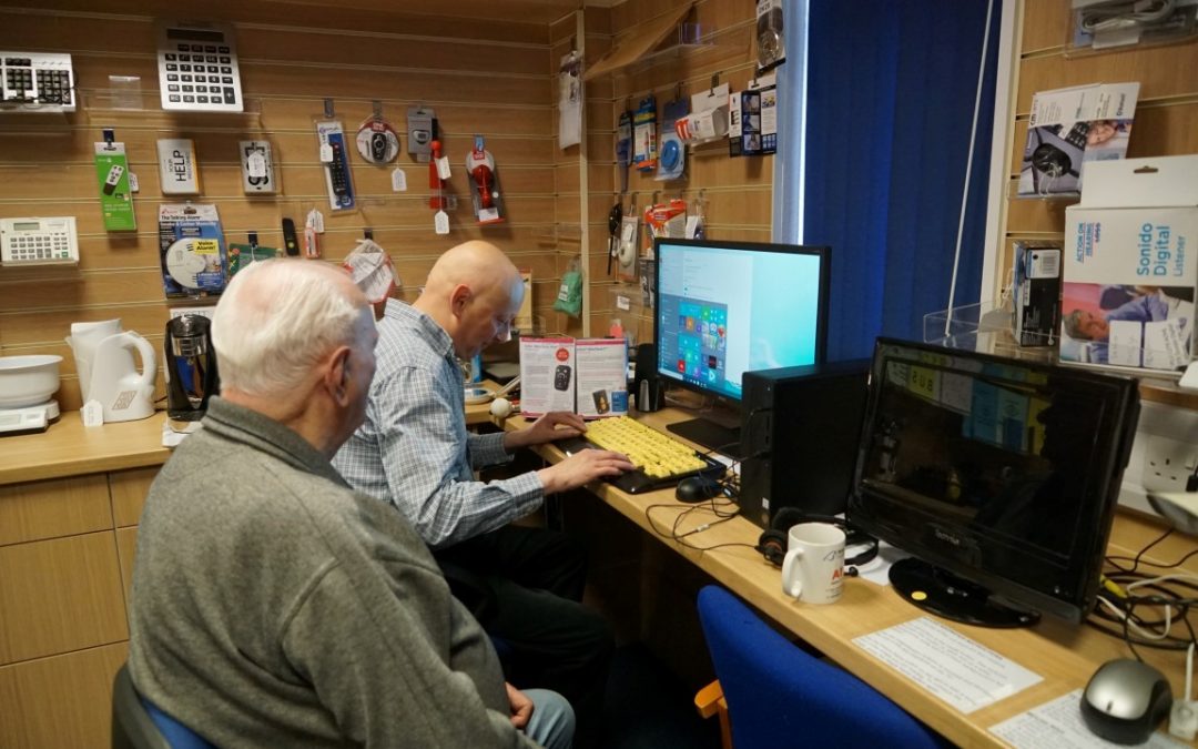 Two older men looking at a computer with an accessible keyboard
