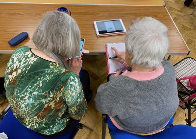 A young man helping an elderly woman with an ipad