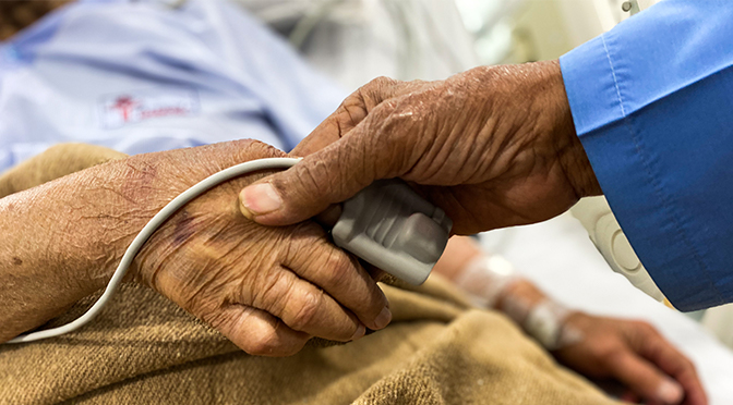 Doctor's hand and old person's hand in a hospital bed